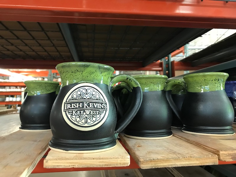 black mugs with green rims and a logo